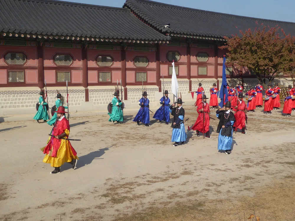 Guards in red, blue and green Joseon-era costume marching with spears and flags at the Gyeongbokgung changing-of-the-guard ceremony