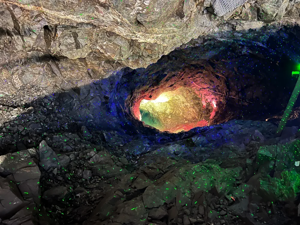 A lit rock chamber inside Gwangmyeong Cave with blue and green points of light across the walls