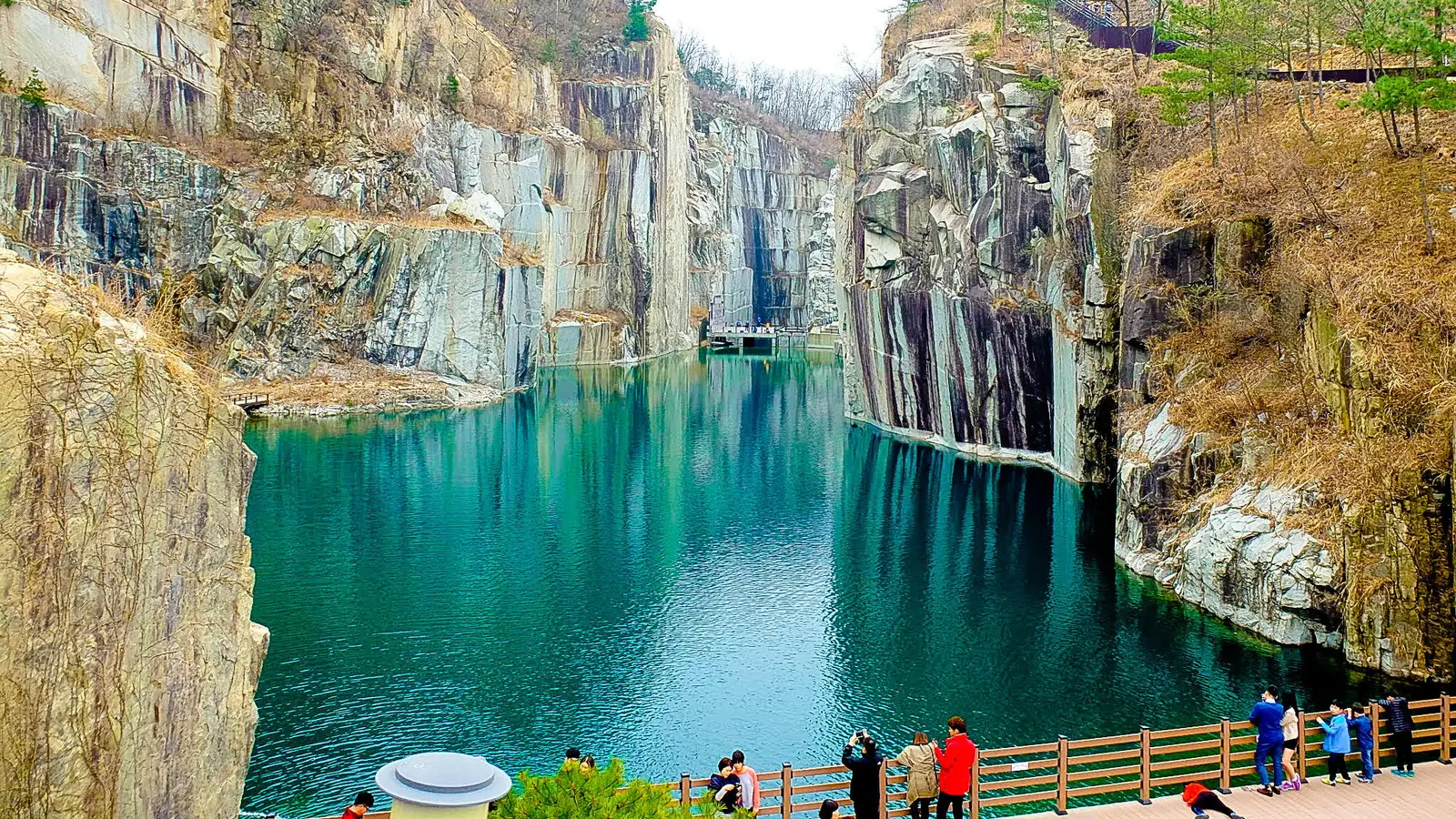 A deep turquoise lake filling a granite quarry with sheer rock walls at Pocheon Art Valley