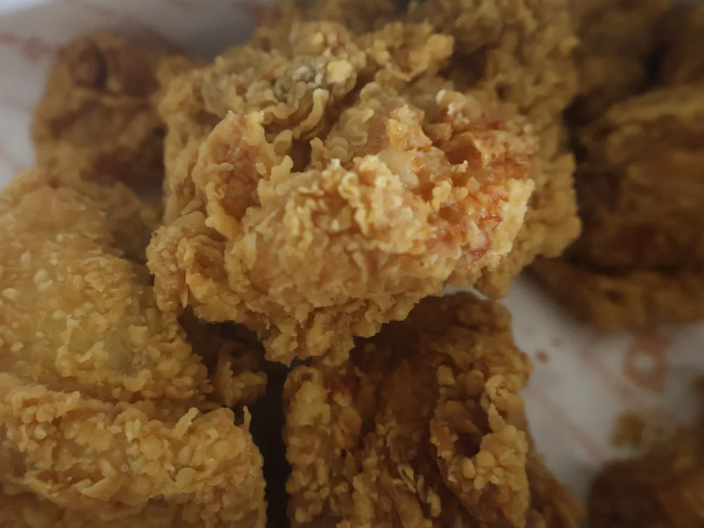 Close-up of plain Korean fried chicken pieces with a thin, craggy, deeply golden crust
