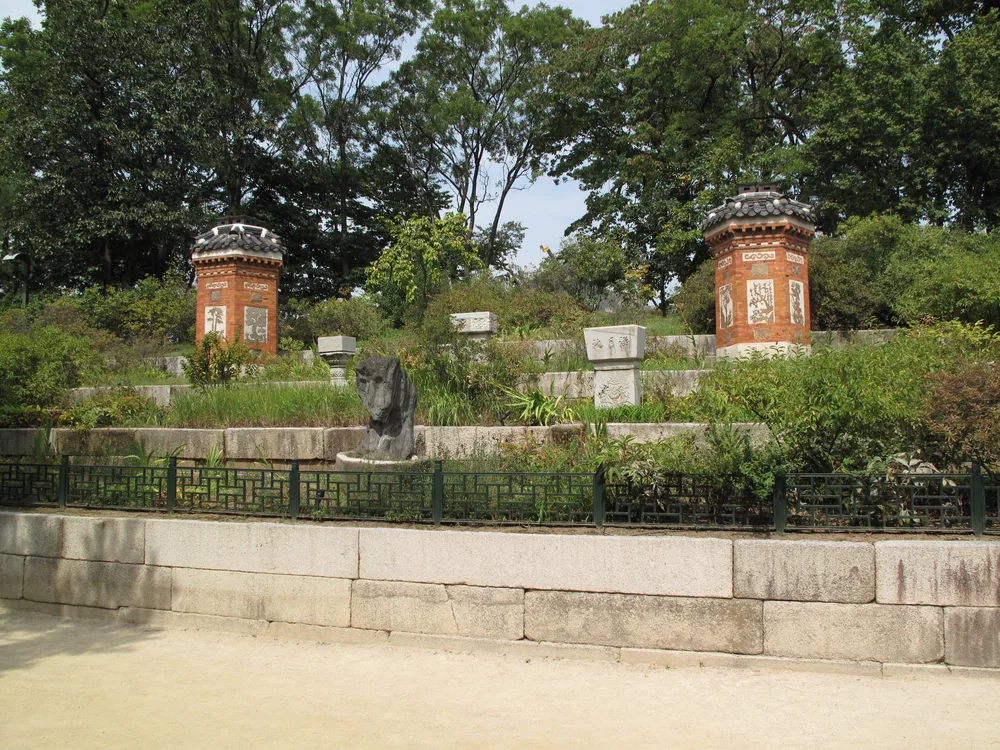 Two ornate brick chimney stacks with tiled caps in a palace garden, part of the ondol underfloor-heating flue system